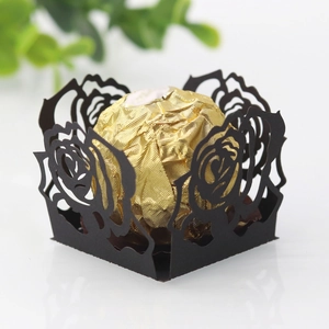 Vue macro de l'emballage en papier noir découpé au laser avec motifs de roses pour chocolats