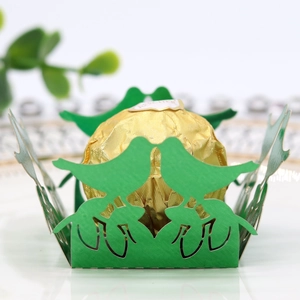 Macro detail of laser cut green bird candy box with hollowed lace and golden chocolate