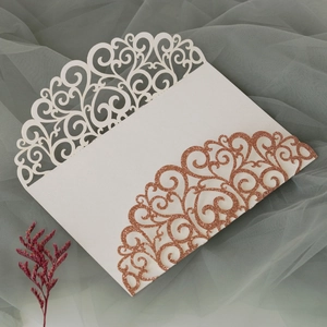 Close-up of laser cut hollow floral pattern on glitter rose gold wedding invitation card