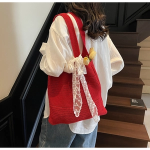 Détail du sac à bandoulière en crochet rouge avec ruban en dentelle et décoration