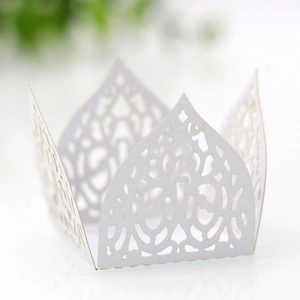 Detail of white laser-cut cupcake wrappers with elegant crown pattern for party decor