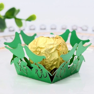Detail of green laser-cut paper wrapper with bird design for chocolates and cupcakes