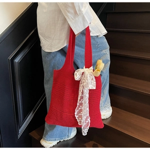 Gros plan sur le sac en crochet rouge avec nœud en dentelle blanche et tulipe jaune