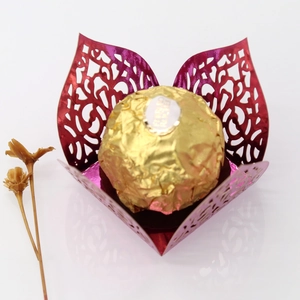 Macro view of laser-cut fuchsia paper chocolate holder with elegant vine patterns