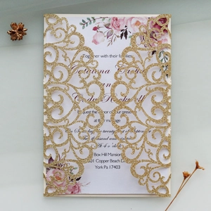 Detail of laser cut glitter wedding invitation with floral insert and intricate scrollwork