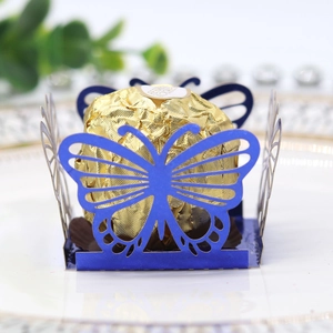 Macro detail of laser-cut blue butterfly chocolate wrapper on white gold-rimmed plate