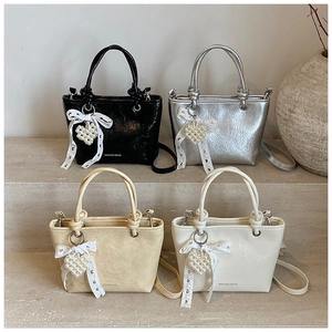 Detailed view of four colorful mini bucket bags with pearl heart charms and lace bows