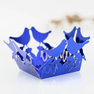 Detail of laser-cut royal blue cupcake wrapper with elegant birds and floral pattern