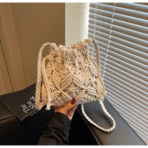 Close-up of white macramé woven bucket bag with wood bead drawstring and intricate knit