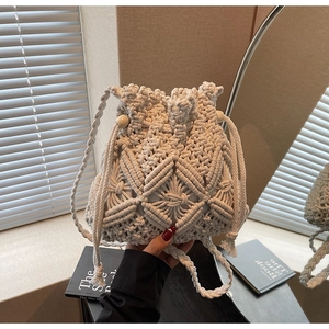 Detail of hand-woven cream bucket bag featuring geometric crochet patterns and wood beads