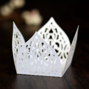 Macro detail of white laser-cut cupcake wrappers with intricate floral lace pattern