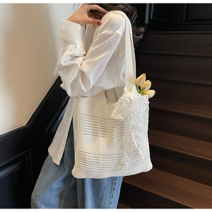 Gros plan d'un sac cabas en tricot blanc avec nœud en dentelle et texture ajourée délicate