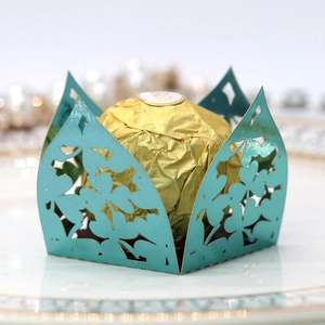 Macro detail of laser-cut mint green chocolate wrapper with floral patterns for wedding