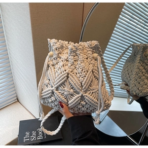 Detail of white macrame bucket bag with geometric patterns and wooden bead accents