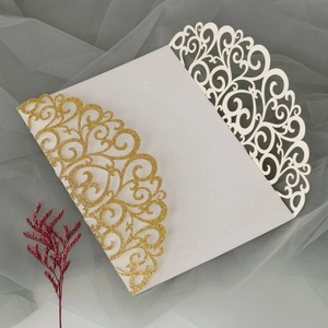 Detail of laser-cut wedding invitation with gold glitter and elegant filigree patterns