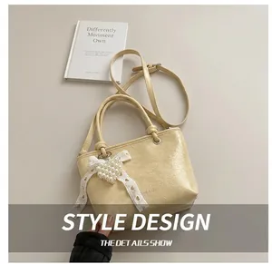 Detailed close-up of cream pleated bucket bag with pearl heart and lace bow accent