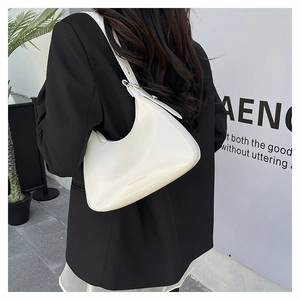 Detail of white PU leather hobo bag with adjustable strap worn by model in black suit