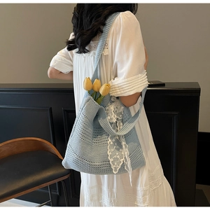 Détail d'un sac cabas au crochet bleu clair avec nœud en dentelle blanche et maille ajourée