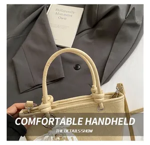 Close-up of cream pleated bucket bag featuring knotted handles and pearl lace charm