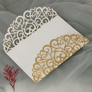 Detailed laser-cut glitter patterns on ivory and gold wedding invitation covers