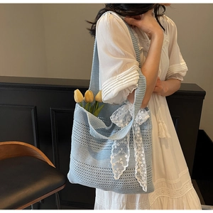 Détail d'un sac cabas au crochet bleu clair avec nœud en dentelle et tulipes jaunes