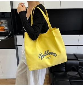 Detail of spacious yellow canvas tote bag featuring artistic text for daily commuting