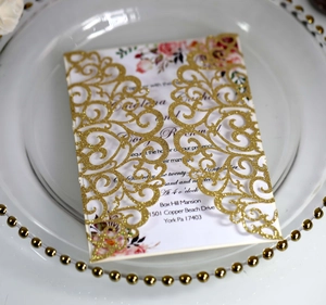Detailed close-up of a gold glitter laser-cut wedding invitation on an elegant white plate