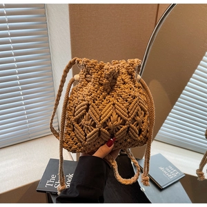 Detailed close-up of handmade woven straw bucket bag with drawstring and pearl beads