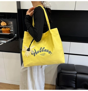 Close-up of bright yellow canvas tote bag with 3D daisy flower and artistic text print