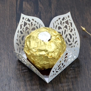 Close-up of laser-cut off-white paper chocolate holder with intricate floral patterns