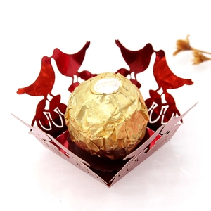 Macro view of laser-cut red bird candy box with hollow design and metallic finish