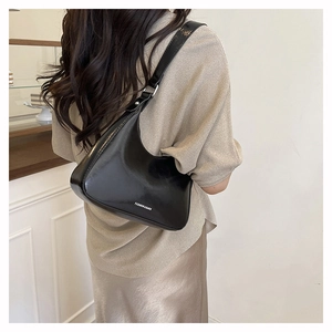 Close-up of black glossy leather hobo bag with white Fashion & Bags text on shoulder