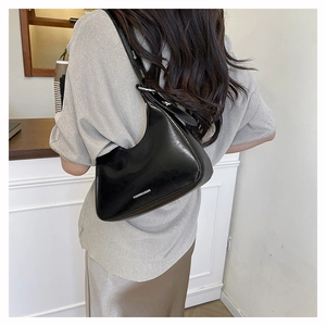 Detail of black patent leather underarm bag with silver buckle and white logo text
