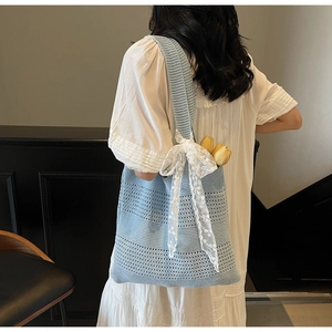 Gros plan du sac fourre-tout en tricot bleu clair avec détails de nœuds en dentelle blanche