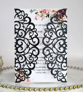 Detail of laser-cut glitter wedding invitation with floral insert and intricate pattern