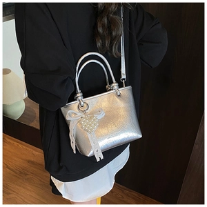 Detail of silver pleated bucket bag with pearl heart pendant and ribbon charm accessory