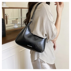 Close-up of a black crescent shoulder bag with white fashion slogan and retro leather texture
