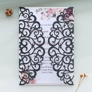Detail of laser-cut black glitter wedding invitation with elegant floral print insert