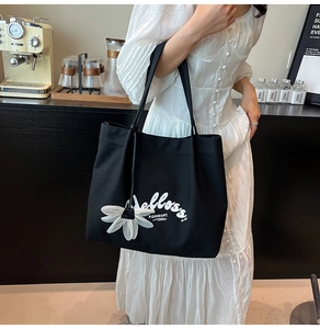 Detail of black canvas tote bag with white floral pendant and Hellow! letter print