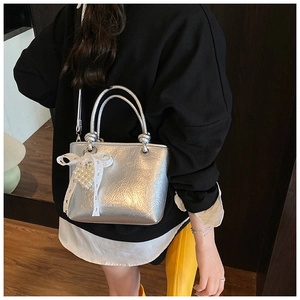 Silver pleated bucket bag featuring metallic texture with lace bow and pearl pendant