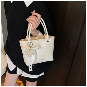 Close-up of cream bucket bag with pearl heart pendant and delicate lace ribbon detail