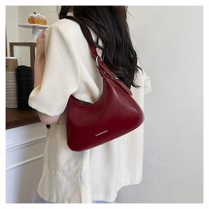 Close-up of a burgundy leather crescent underarm bag with silver metallic hardware detail