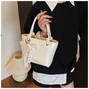 Detail of cream bucket bag featuring pearl heart charm and lace ribbon decoration