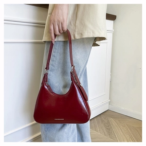 Detail of burgundy glossy leather underarm bag with Fashion & Bags embossing