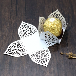 Detail of white laser-cut lace chocolate wrapper in flat and folded 3D floral shape