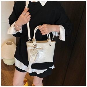 Close-up of creamy white bucket bag with lace bow and pearl heart charm detail
