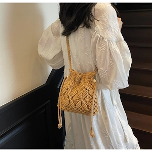 Close-up of woven straw bucket bag with drawstring and tassel details on white dress