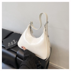 Detailed shot of white hobo bag with glossy finish and silver buckle on black leather seat