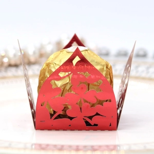 Close-up of red laser-cut clover pattern favor box with a gold foil chocolate