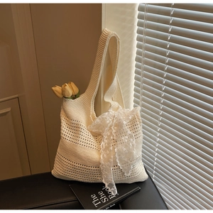 Détail de la maille ajourée et du nœud en dentelle sur ce sac fourre-tout crème